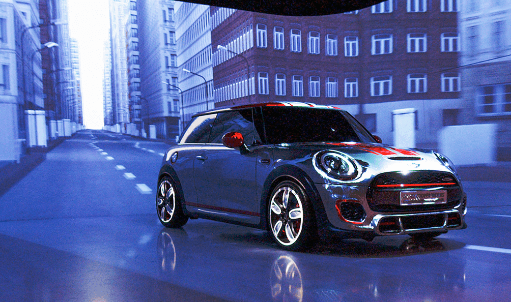 Mini stands in front of a projected city scene